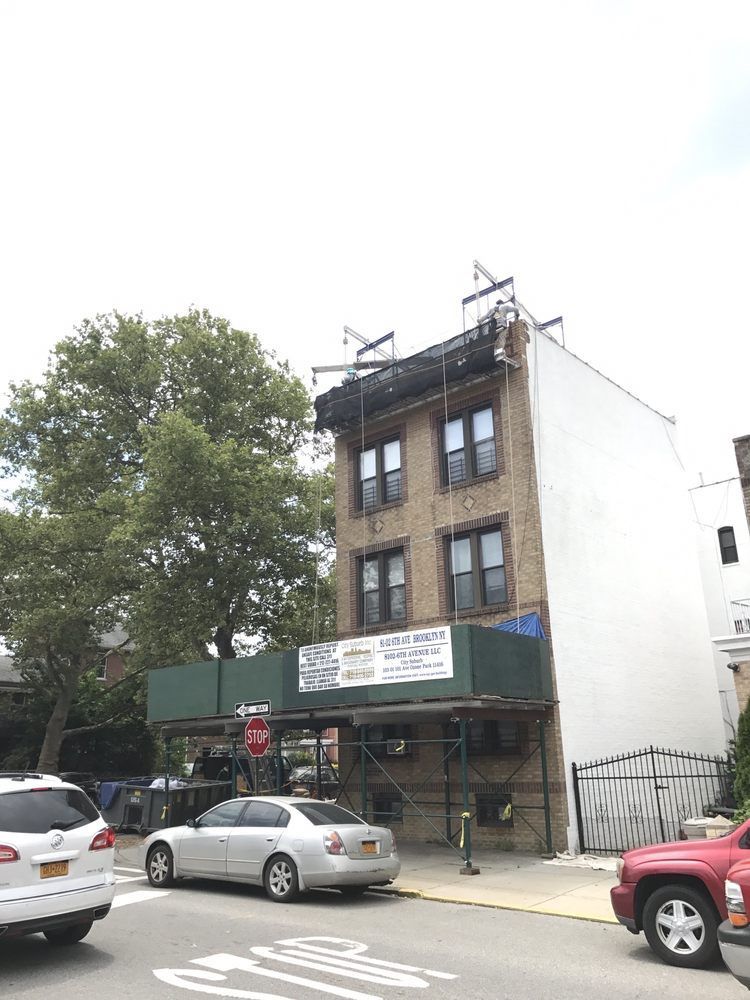 A building under construction with cars parked in front of it.