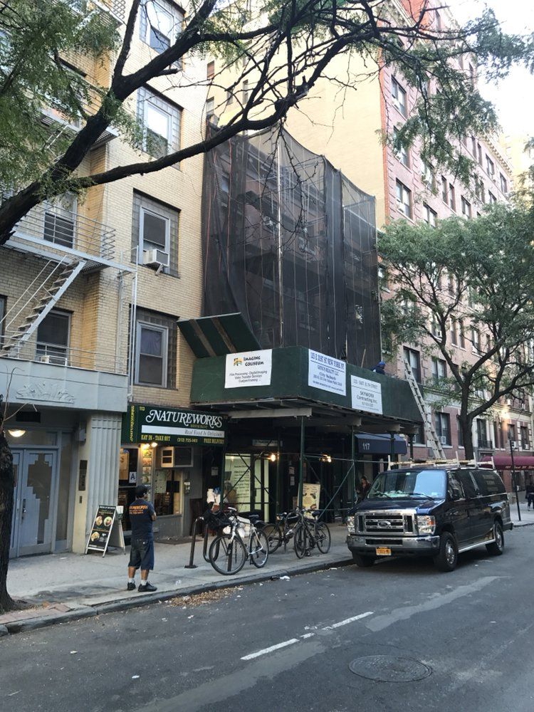 A van is parked on the side of the road in front of a building under construction.