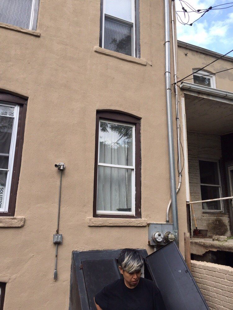 A man is standing in front of a building holding a couch.