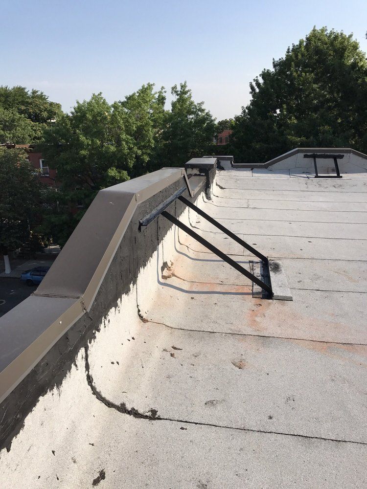 A roof with a railing and trees in the background