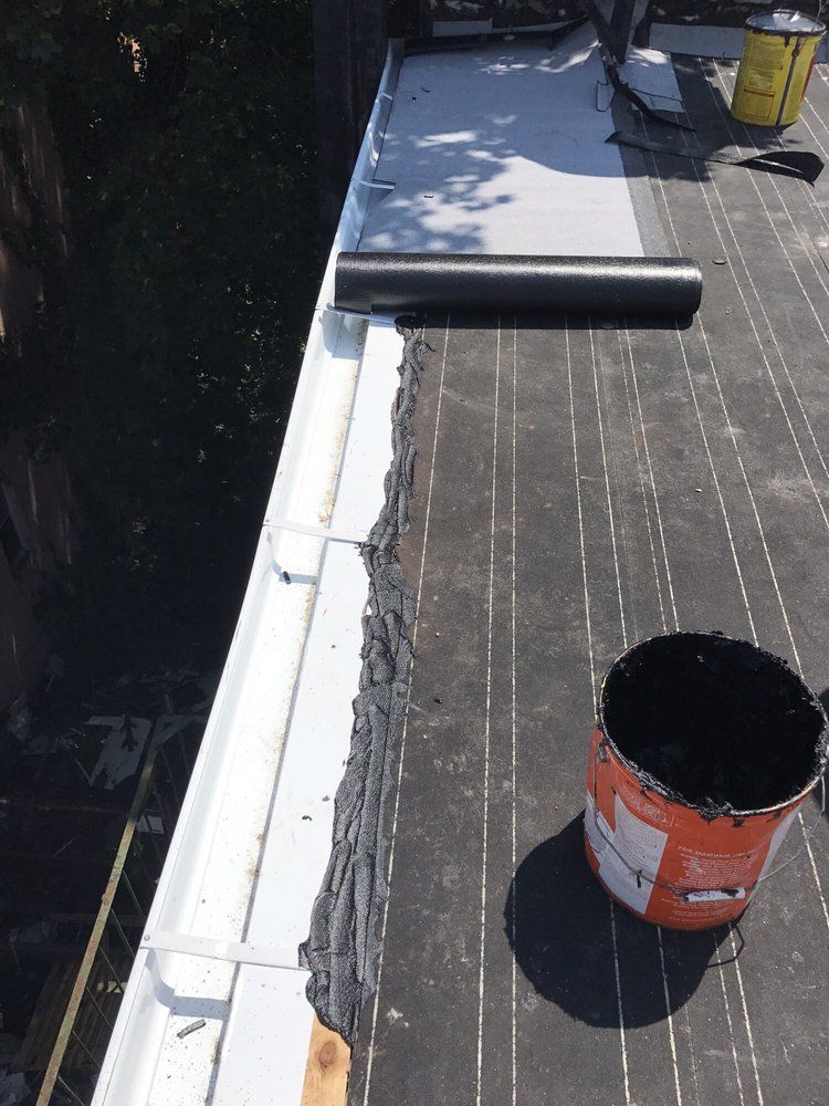 A bucket of black paint is sitting on a roof