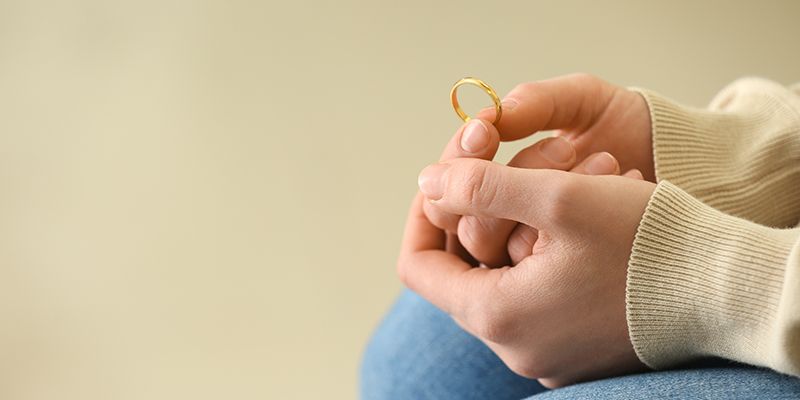 A woman is holding a wedding ring in her hands.