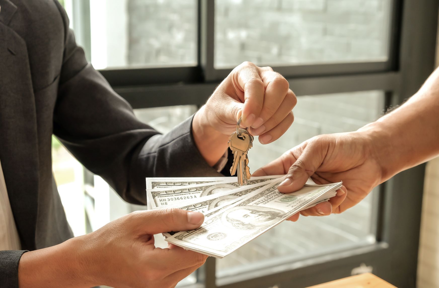 A man is handing a woman a bunch of money and keys.