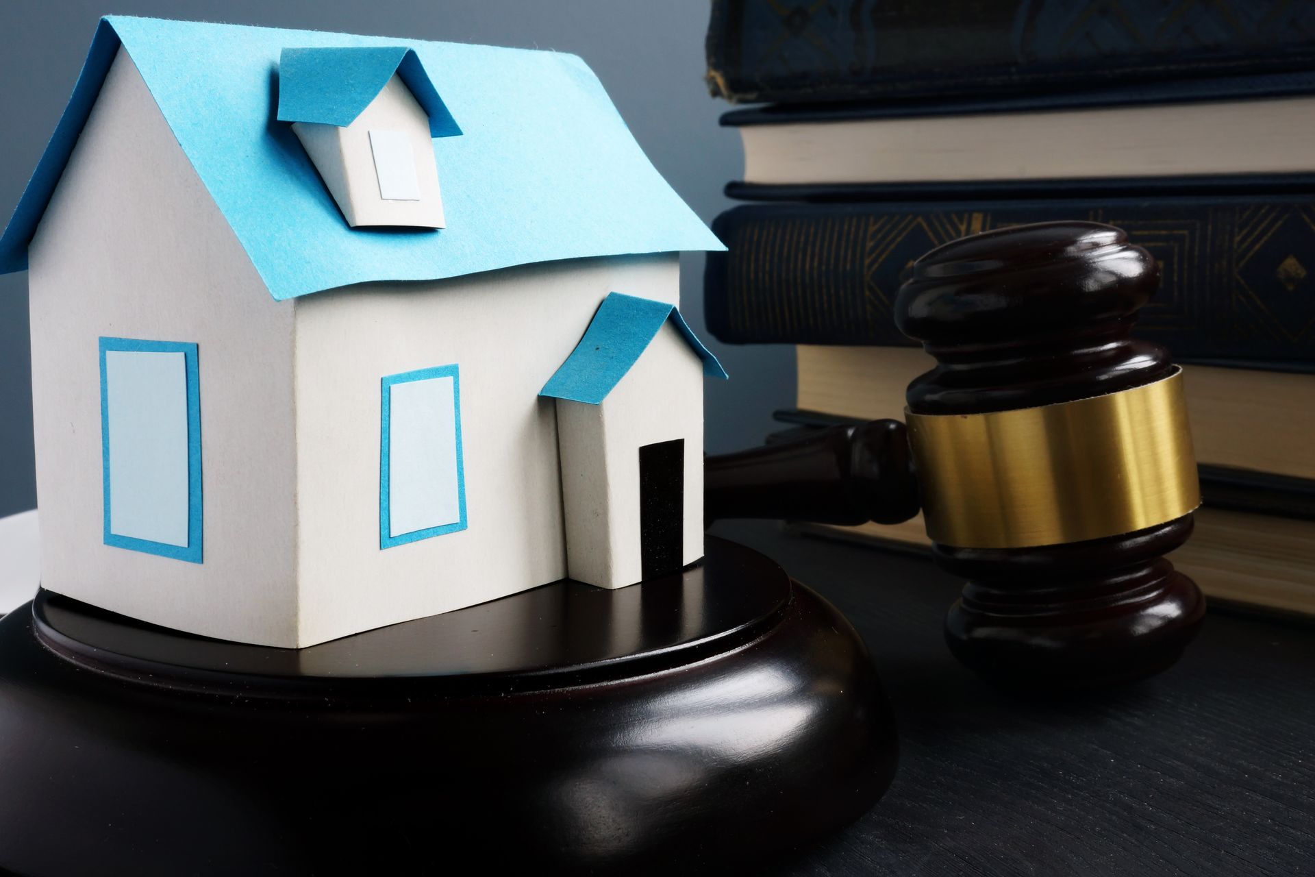 A model house is sitting on top of a wooden block next to a judge 's gavel.
