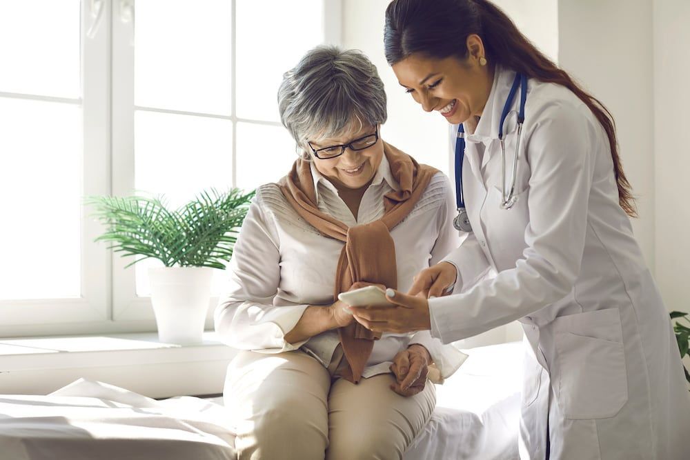 A doctor is talking to an elderly woman who is sitting on a bed.
