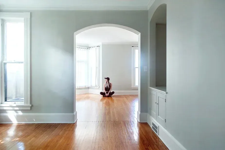 An empty living room with hardwood floors and gray walls.