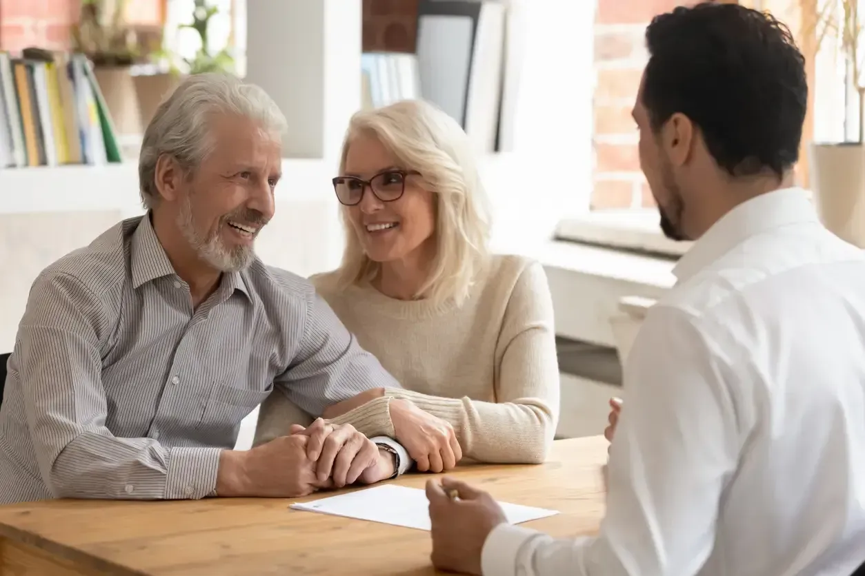 An older couple is sitting at a table talking to a man.