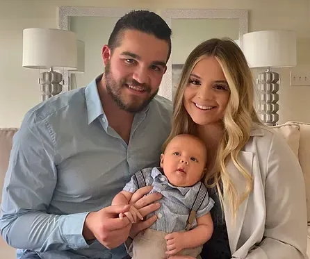 A man and woman are posing for a picture with a baby.