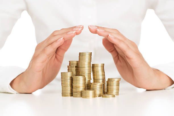 A person is covering a pile of coins with their hands.