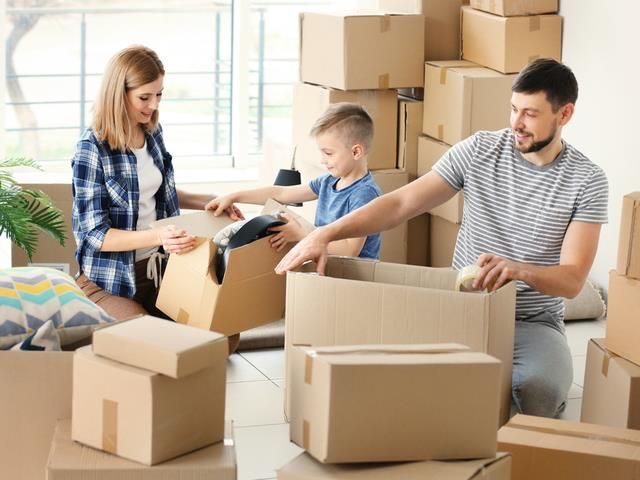 A family is packing boxes in a living room.