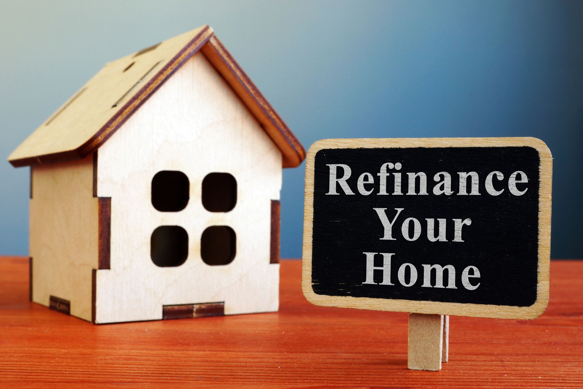 A small wooden house next to a sign that says refinance your home