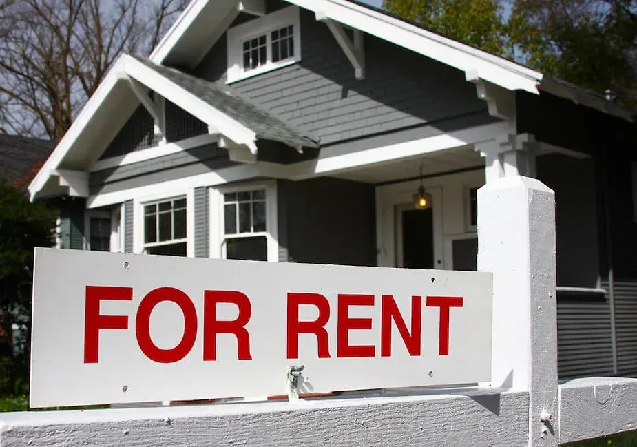 A house with a for rent sign in front of it