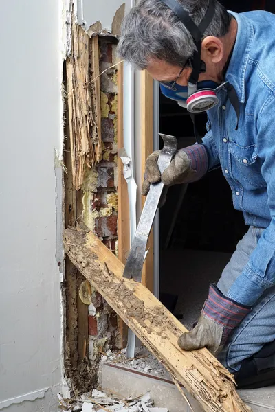 A man wearing a gas mask is cutting a piece of wood with a saw