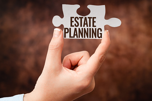 A person is holding a piece of puzzle with the words `` estate planning '' written on it.