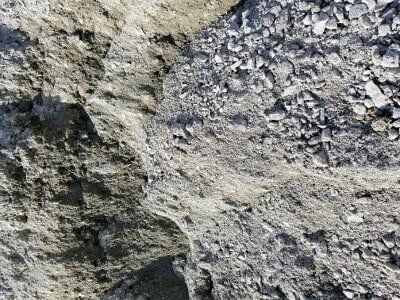 Close-up of rough gray and tan rock surface with cracks and textures