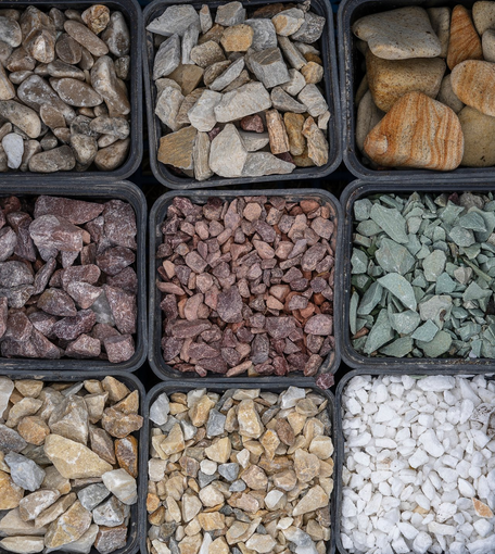 Trays of assorted decorative stones and gravel in brown, gray, red, green, and white