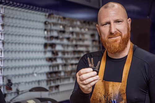 A Man With A Beard Is Holding A Key In His Hand - Bolingbrook, IL - Master Locksmithing Inc