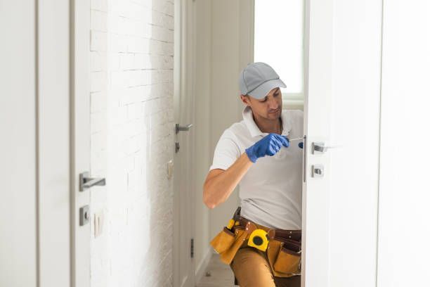 A Man Is Fixing A Door With A Screwdriver In A Hallway - Bolingbrook, IL - Master Locksmithing Inc