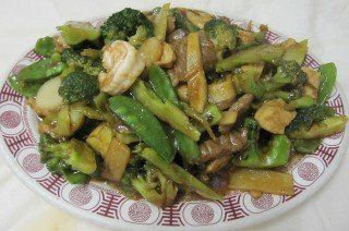 Stir-fry with broccoli, snap peas, and meat on a patterned plate.