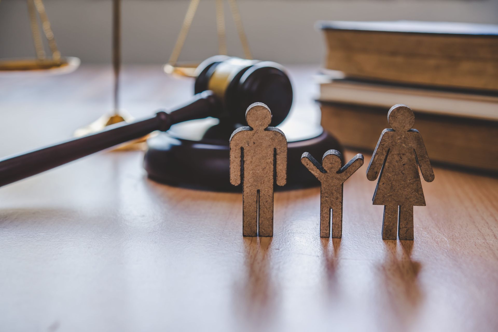Mini wooden family figures beside a judge’s gavel on a desk, suggesting a custody or family law case