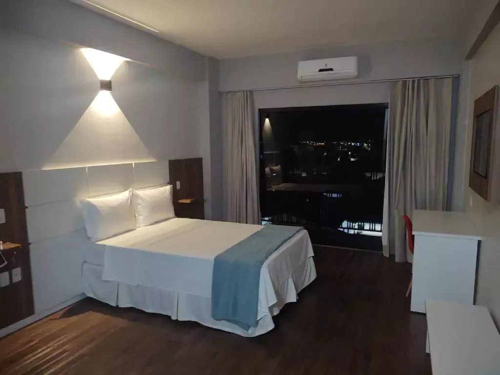 Um quarto de hotel com uma cama king size e uma varanda Hotel Quartzo Cristalina