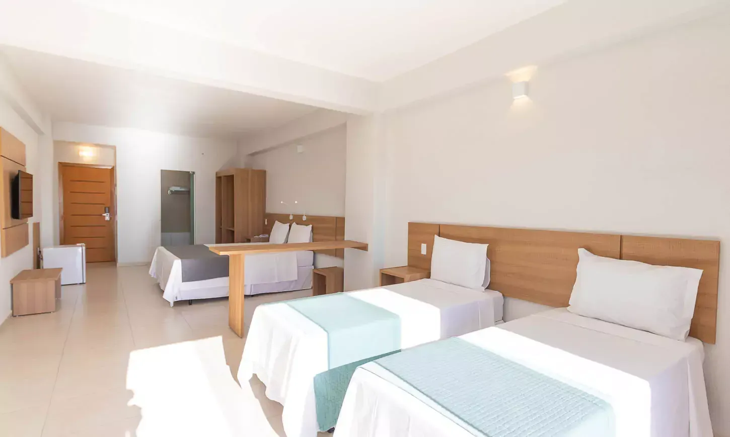 Um quarto de hotel com três camas e uma televisão Hotel Quartzo Cristalina
