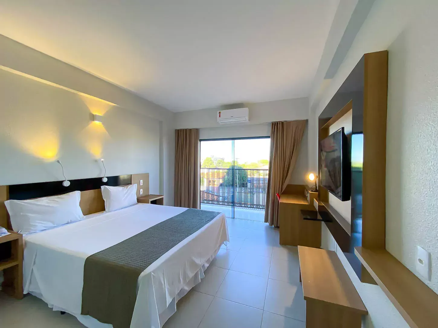 Um quarto de hotel com uma cama king size e uma TV de tela plana Hotel Quartzo Cristalina