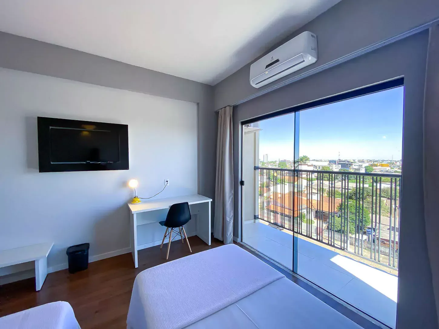 Um quarto de hotel com duas camas, uma escrivaninha, uma TV de tela plana e uma varanda Hotel Quartzo Cristalina