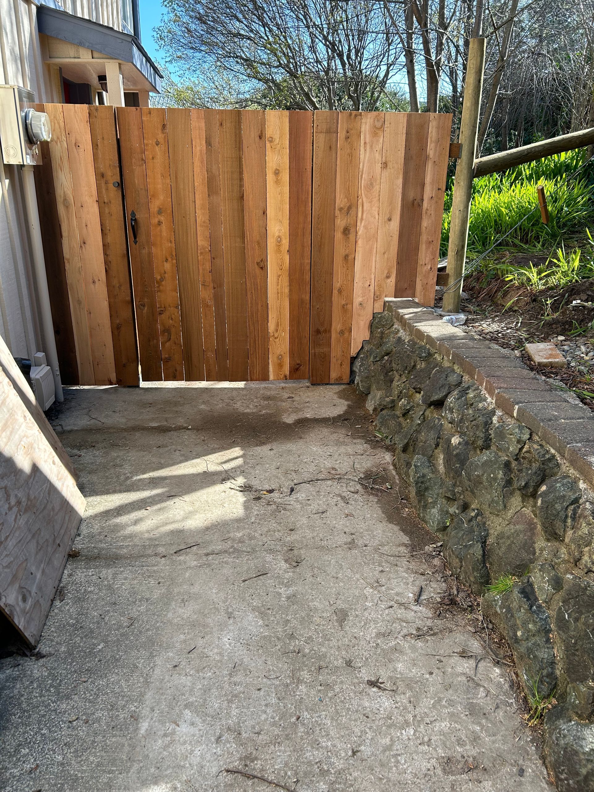 A wooden fence is sitting next to a stone wall.