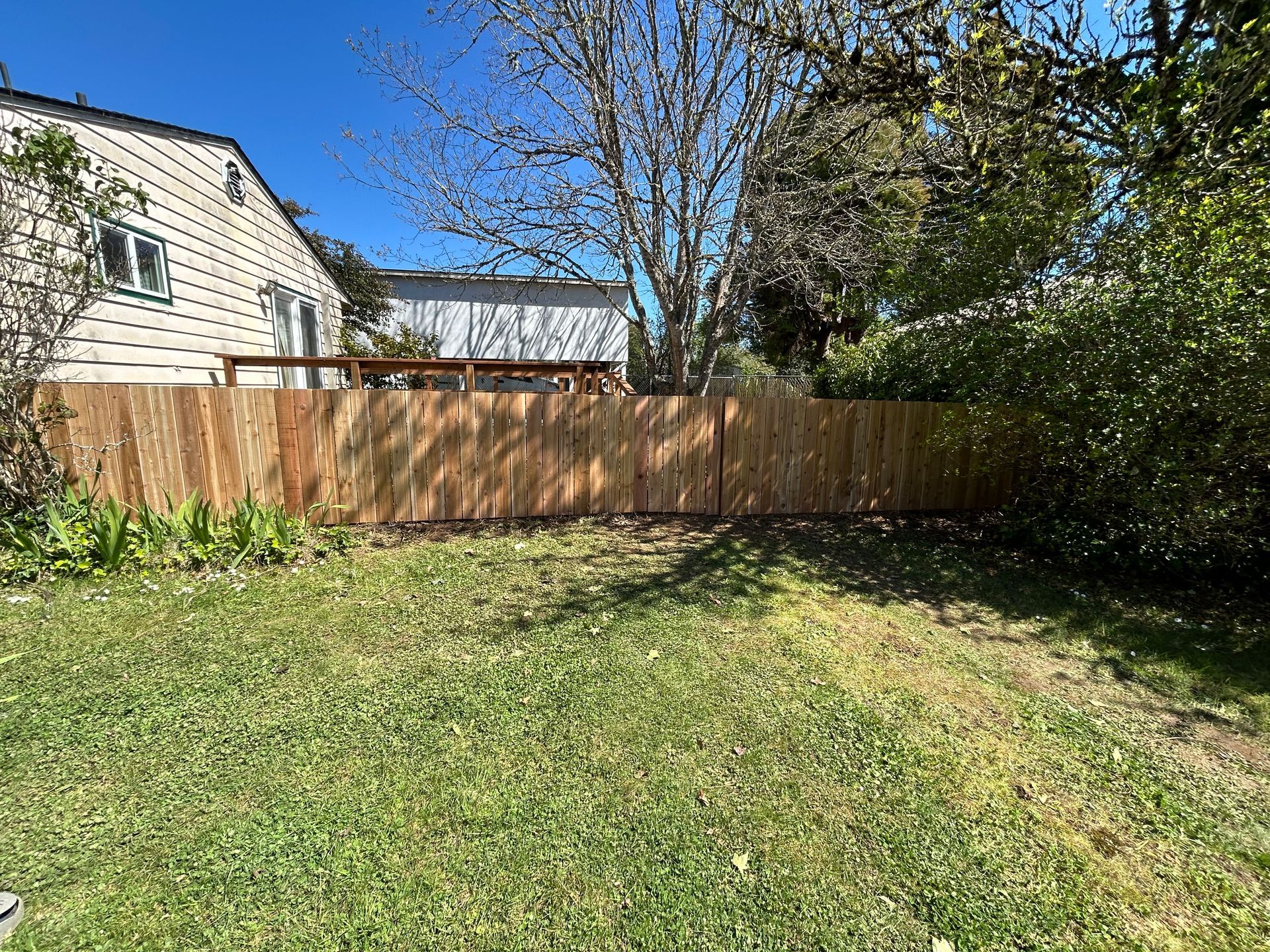 There is a wooden fence in the backyard of a house.