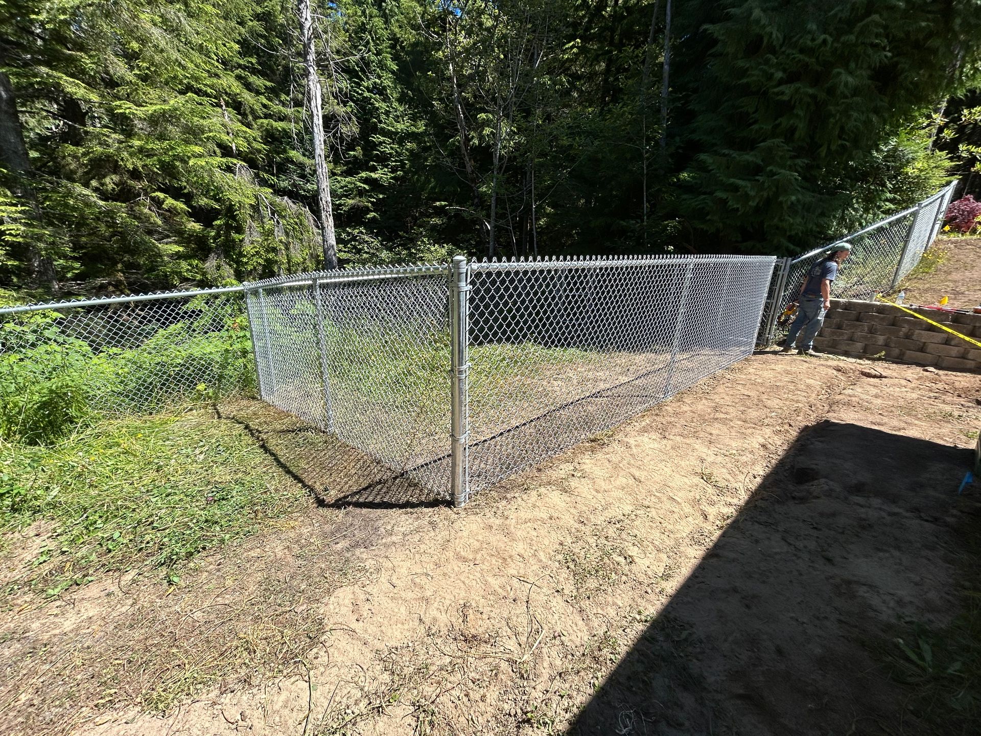 A chain link fence is sitting on top of a dirt hill.