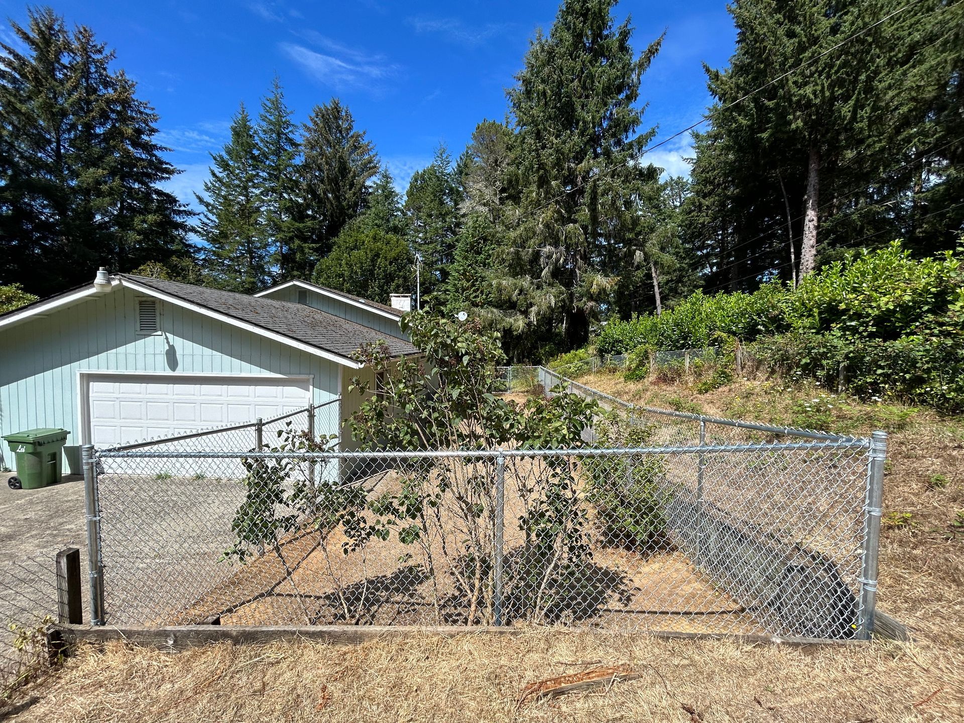 A chain link fence surrounds a garden in front of a house.