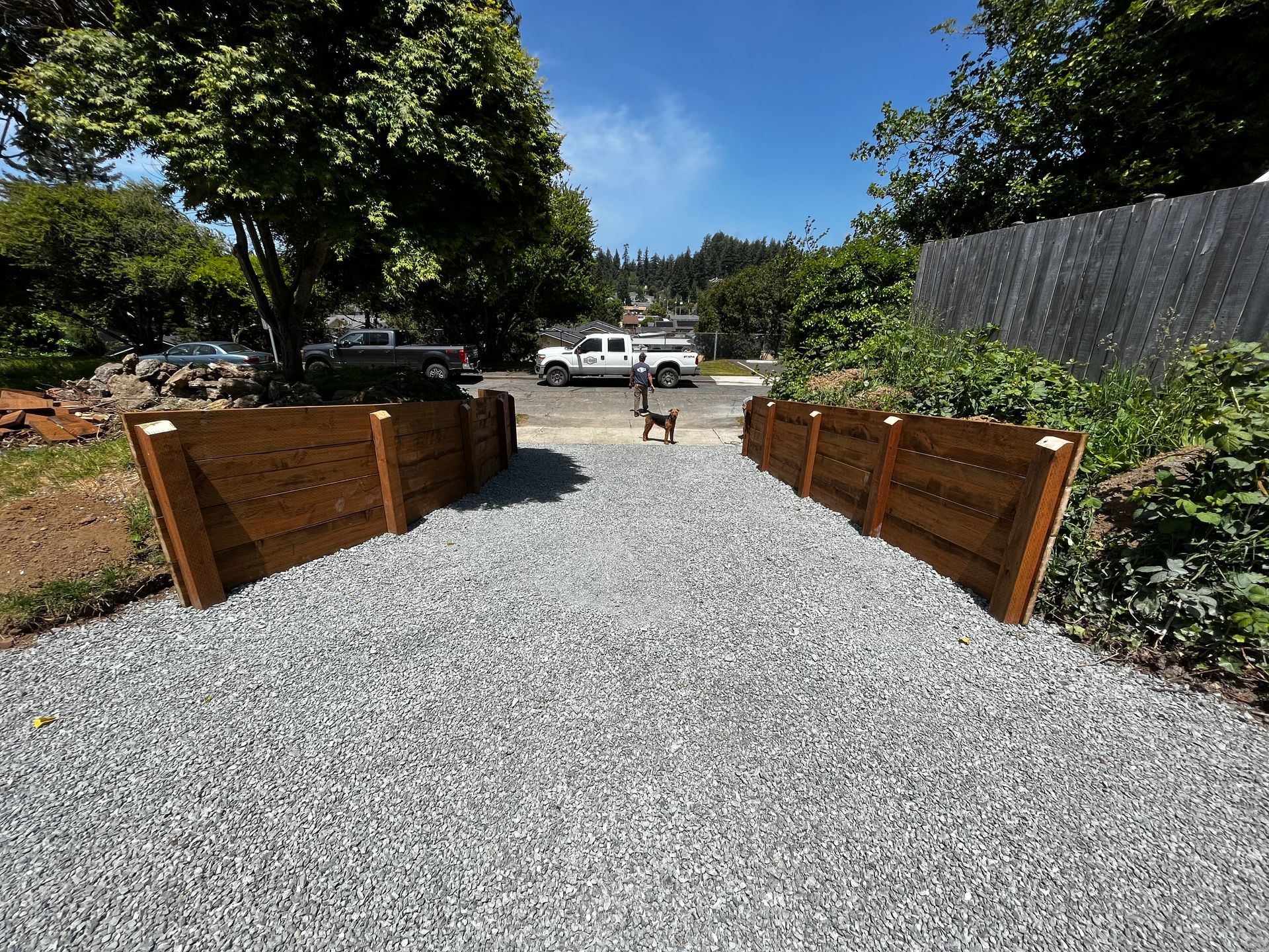 A gravel driveway with a wooden fence in the background