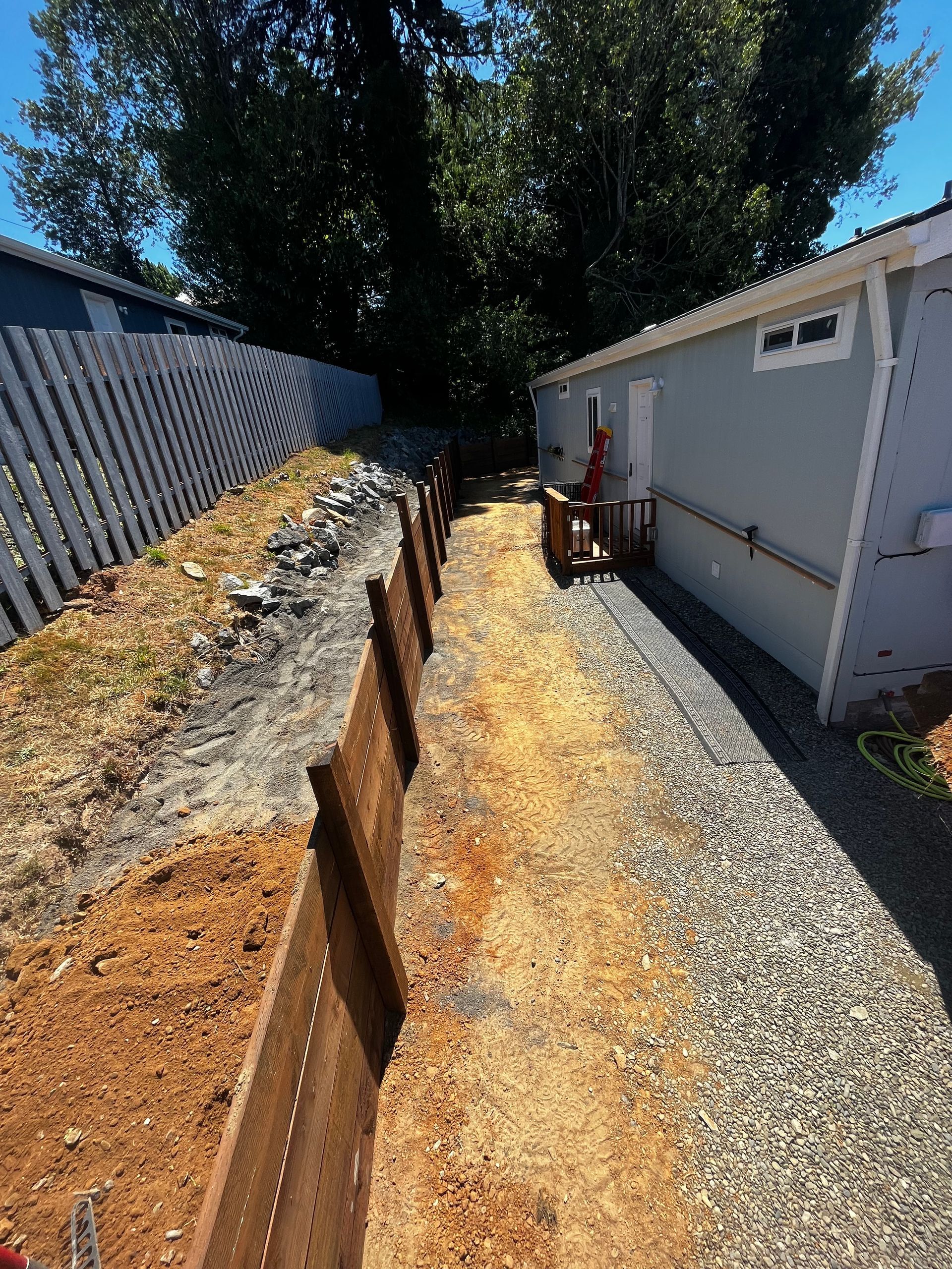 A dirt path leading to a house with a wooden fence.