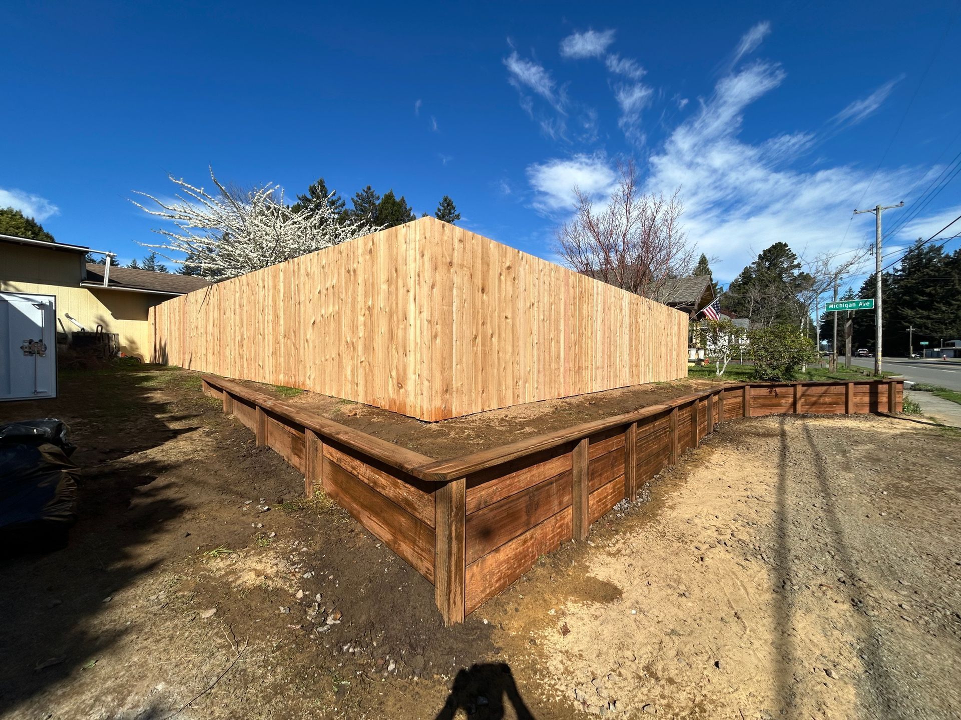 Wooden structure under construction on a raised foundation, with plywood walls and a dirt yard under a blue sky