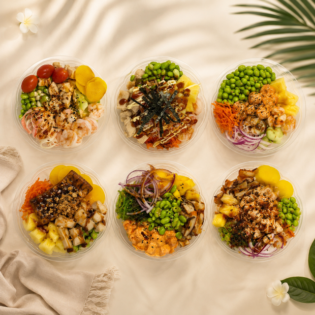 Six colorful grain bowls with vegetables and toppings arranged on a beige cloth.