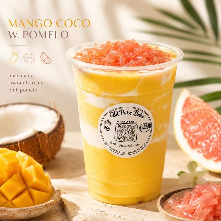 Mango coconut pomelo drink in clear cup with pink topping, beside sliced mango and grapefruit halves