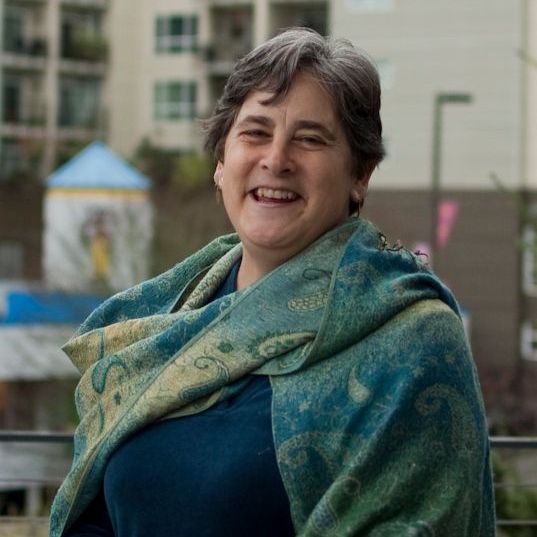 a woman wearing a blue shirt and a green scarf is smiling .