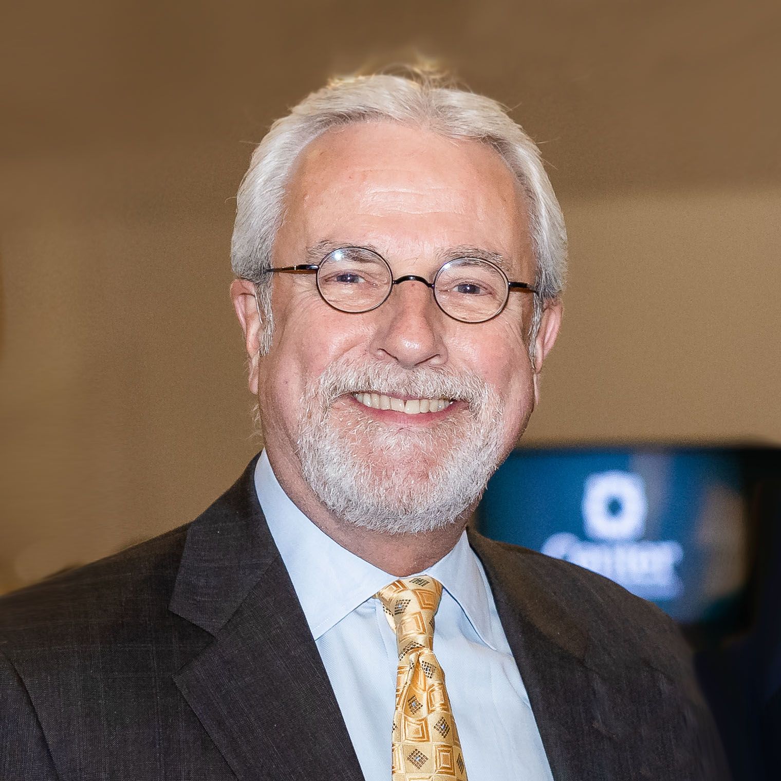 A man with glasses and a beard is wearing a suit and tie.