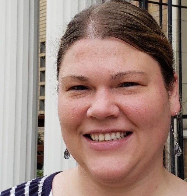 a woman is smiling for the camera and wearing a striped shirt .