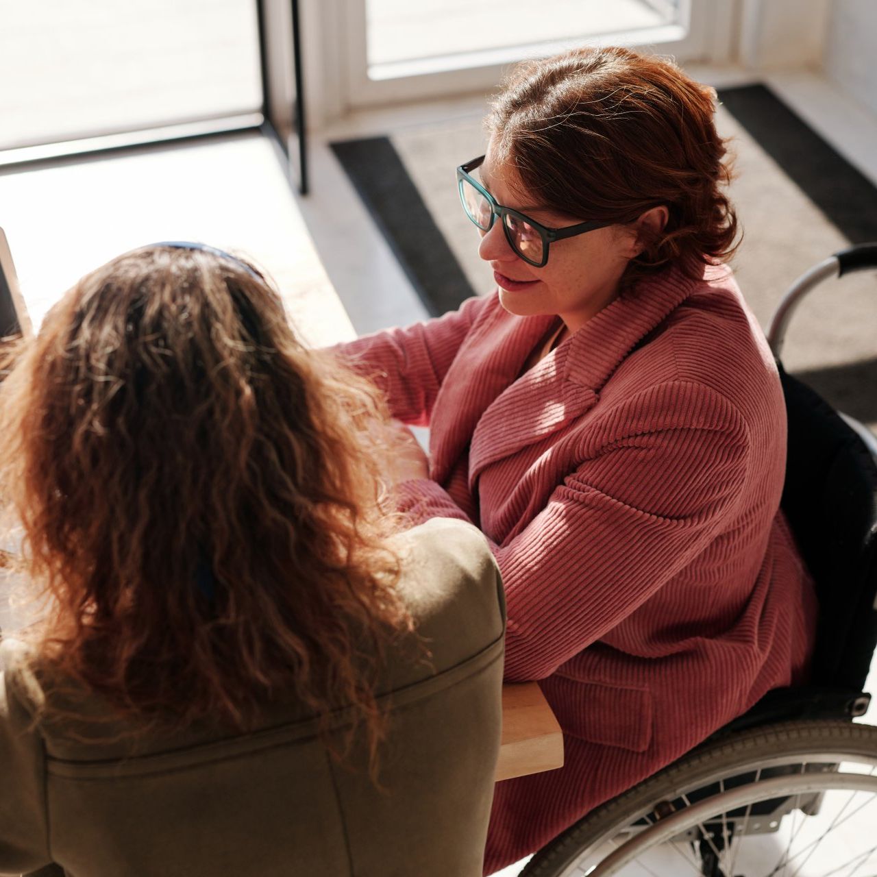 a woman in a wheelchair is talking to another woman