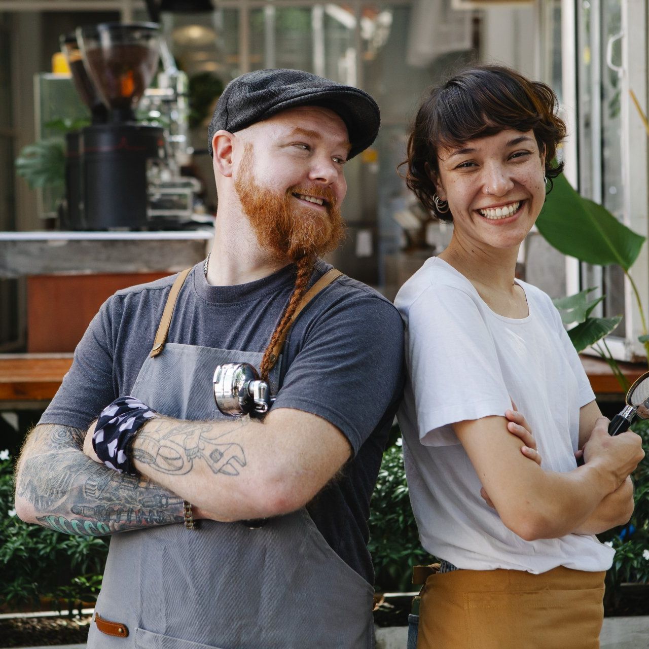 A man and woman smiling with their arms crossed, while back-to-back.