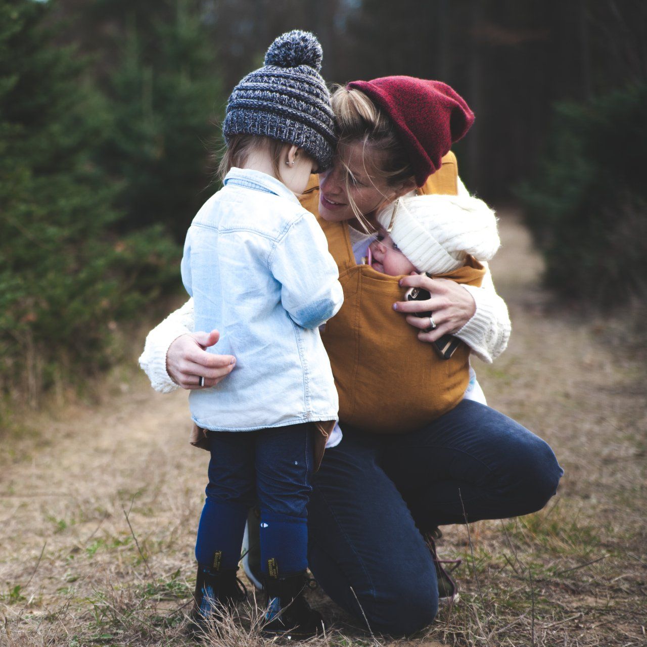 a woman is kneeling down holding a baby in a sling