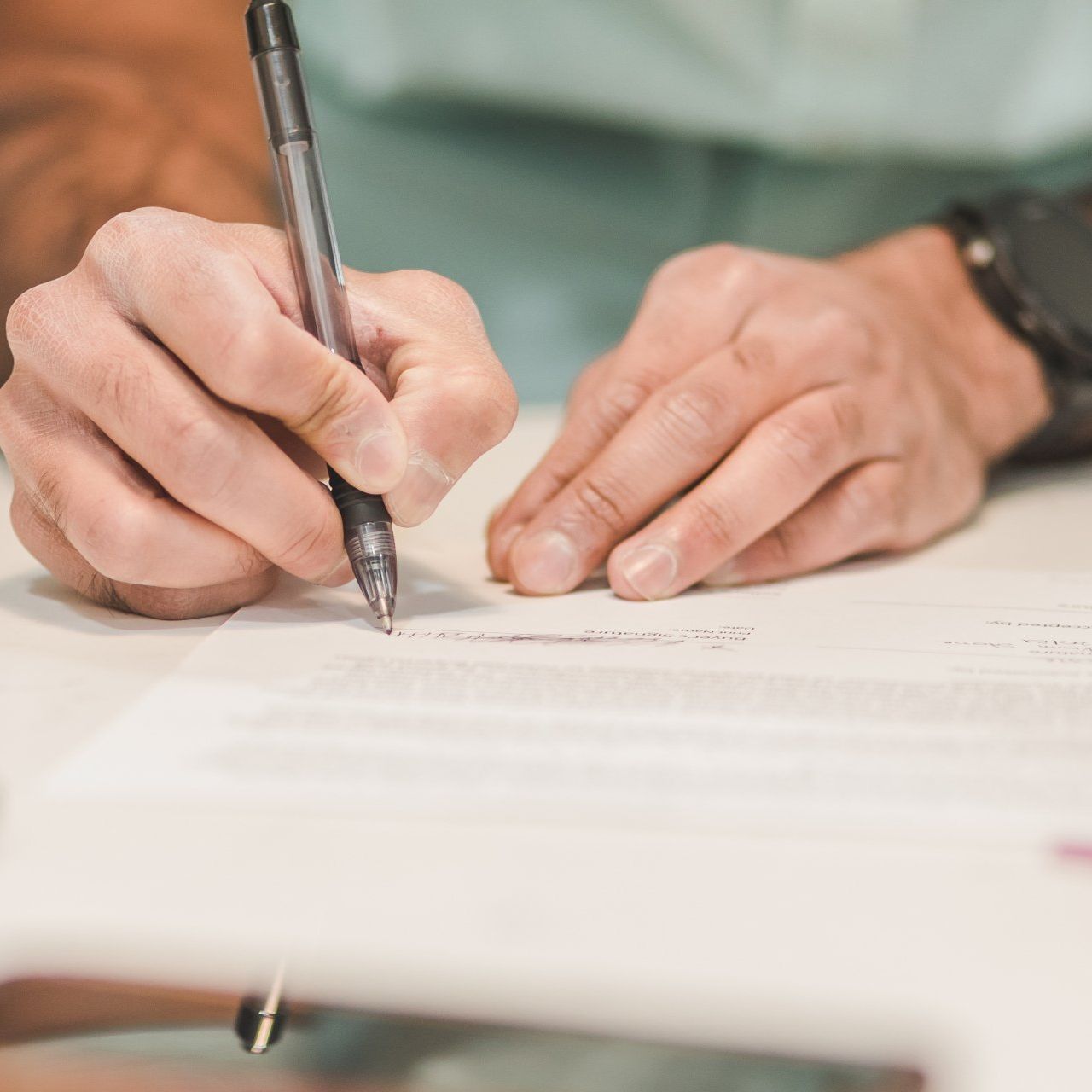 a person is writing on a piece of paper with a pen .