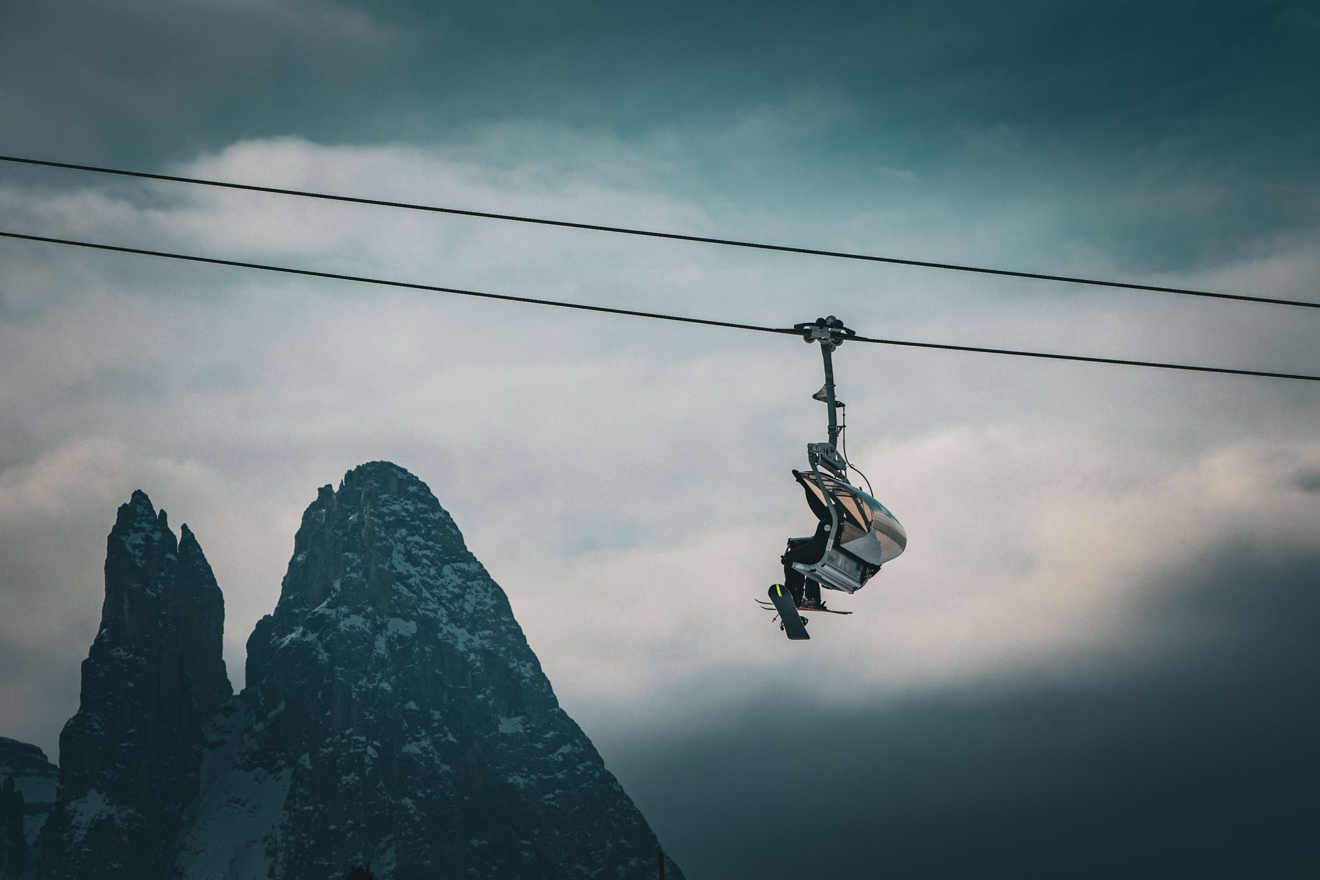 A person ziplining over misty mountains under a cloudy sky