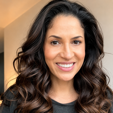 Smiling woman with long dark wavy hair against a warm beige background