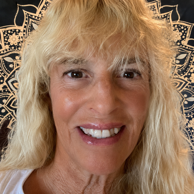 Close-up smiling blonde person against a patterned dark background