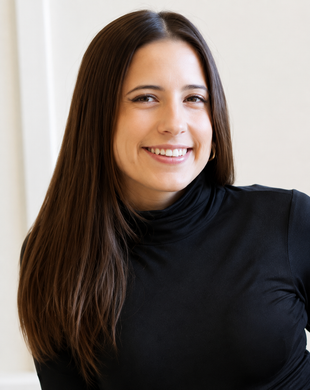 Smiling person with long dark hair in a black turtleneck against a light background