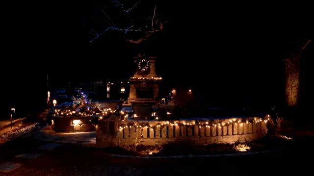 Stone structure lit with string lights at night.