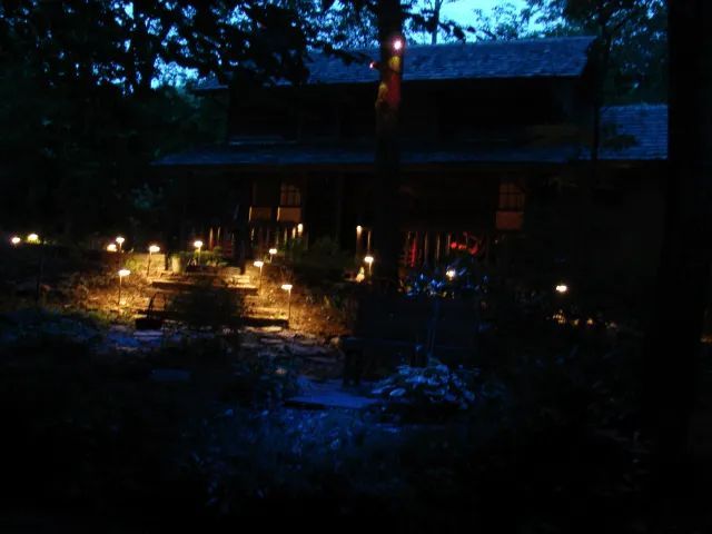 A two-story building in the evening with garden lights illuminating a stone path leading up to it.